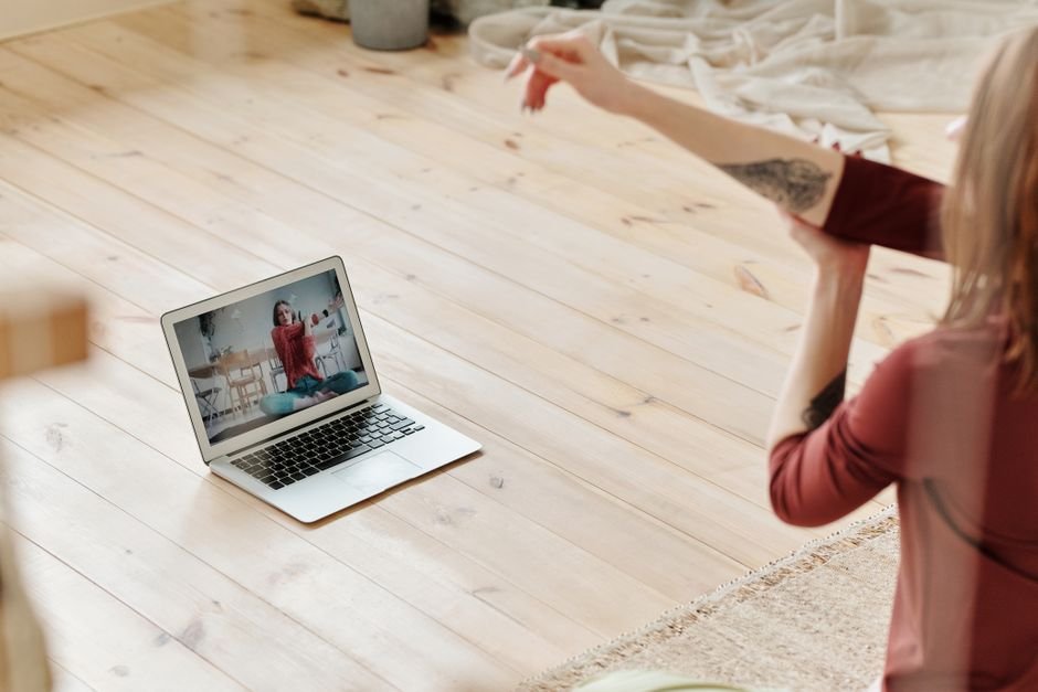 Woman following a telehealth physical therapy session on a laptop at home